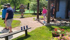 A wooden bench with cups and a sign for a water attraction.