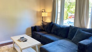 Un salon moderne avec un canapé gris, une petite table blanche et une lampe.