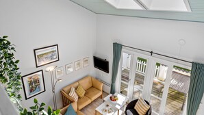 A modern living room with a sofa, a coffee table, and a TV. There are framed pictures on the wall and a plant in the corner. - Cozy home in Vestervig with sauna (Vestervig)