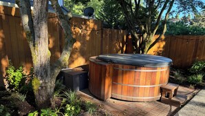 A wooden hot tub with a bench and a small table, surrounded by a wooden fence and garden plants. - Charming Green Lake Craftsman – Hot Tub, AC, Dog Friendly, Walk to Lake & C... (Seattle)