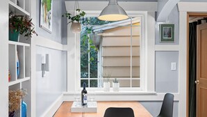 A dining area with a wooden table, black chairs, a hanging pendant light, and potted plants. - Charming Green Lake Craftsman – Hot Tub, AC, Dog Friendly, Walk to Lake & C... (Seattle)