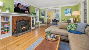 A living room with a fireplace, a television, a sofa, and a dining area. - Charming Green Lake Craftsman – Hot Tub, AC, Dog Friendly, Walk to Lake & C... (Seattle)