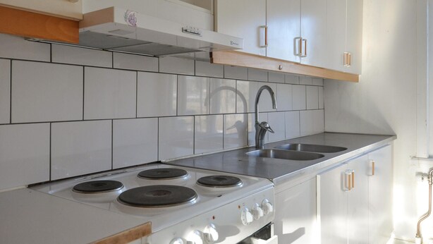 Een keuken met witte kasten, een fornuis en een spoelbak.