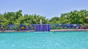 A swimming pool with a blue fence, surrounded by lush greenery. - Oceanwalk 8-504 - A 3 bed 2 bath Seabreeze escape (New Smyrna Beach)