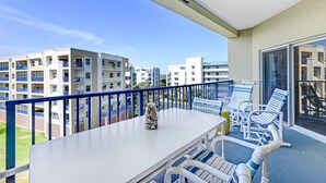 A balcony with a table and chairs, a vase, and a view of surrounding buildings. - Oceanwalk 8-504 - A 3 bed 2 bath Seabreeze escape (New Smyrna Beach)