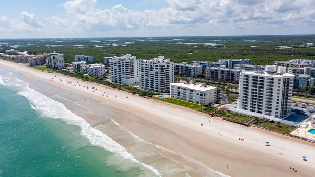 A coastal residential area with beachfront properties, including high-rise buildings and a sandy beach. - Oceanwalk 8-504 - A 3 bed 2 bath Seabreeze escape (New Smyrna Beach)