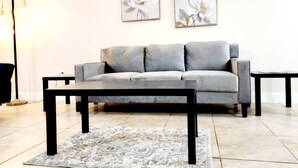 A living room with a grey sofa, a black coffee table, and a patterned rug. - Toria Suites 920 (Lakeland)