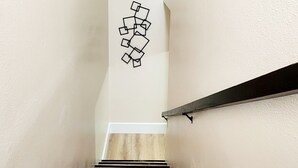 A staircase with black and white steps, a black handrail, and a wall-mounted geometric light fixture. - Toria Suites 920 (Lakeland)
