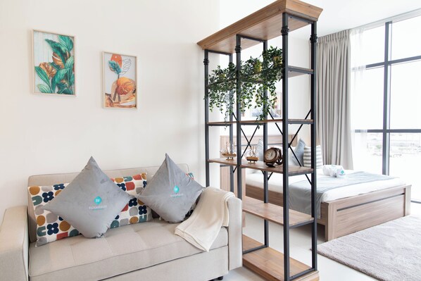 A modern bedroom with a bed, a sofa, and a plant shelf. - Bloomfields Artistic STU in The View (Abu Dhabi)