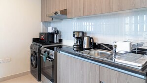 A modern kitchen with stainless steel appliances, a built-in oven, and a coffee maker. - Bloomfields Artistic STU in The View (Abu Dhabi)