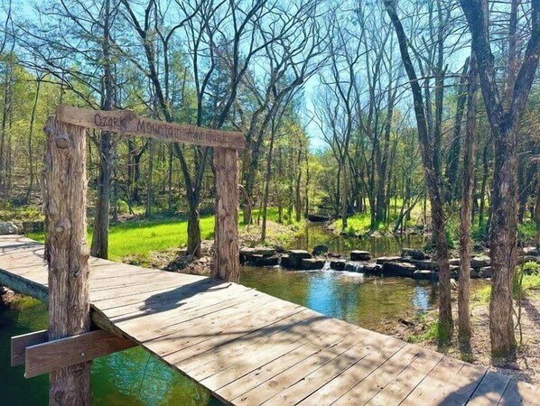 A wooden bridge over a stream with a sign that reads "Ozark Mountain Adventure."