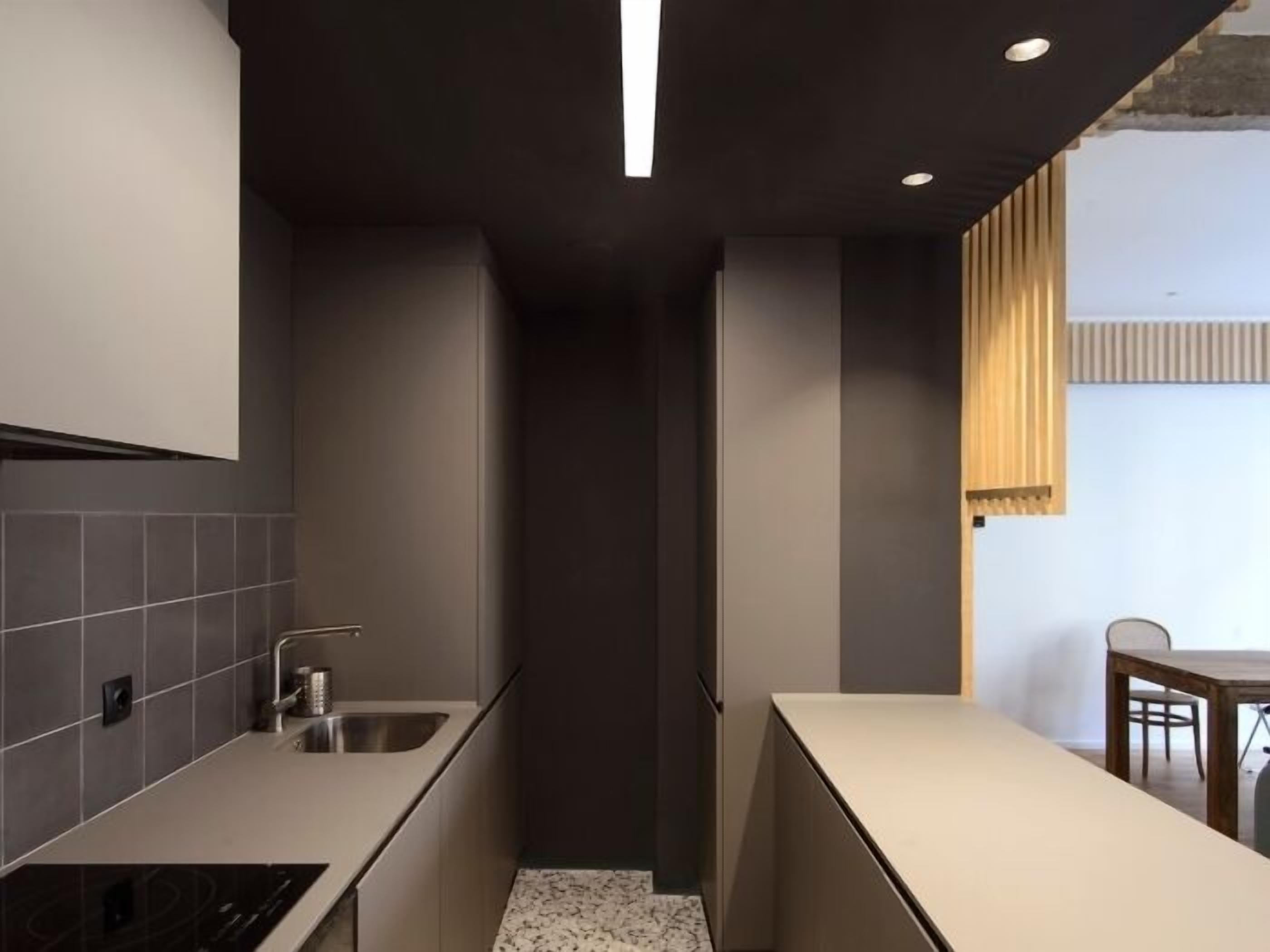 A modern kitchen with dark cabinetry, a stainless steel sink, and a countertop.