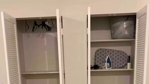 Armario espacioso con puertas abiertas, que incluye estantes y espacio para colgar.