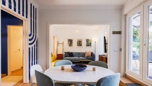 Een eethoek met een ronde tafel, stoelen en een blauwe kom. Achtergrond is een bank en een salontafel.