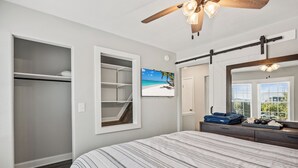 Un dormitorio con cama, armario, televisor y un espejo grande.