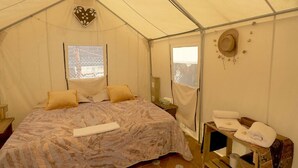 A tented room with a bed, a window, a hat on the wall, and a small table with towels. - Glamping in Quimixto 5 minutes from the beach (Quimixto)