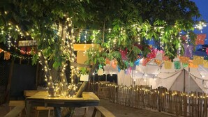 An outdoor dining area with string lights, wooden tables, and a tented structure in the background. - Glamping in Quimixto 5 minutes from the beach (Quimixto)