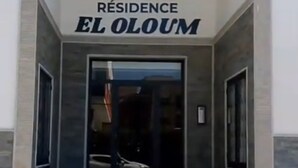 Indgangen til en bygning med et skilt, der siger "RESIDENCE EL OLOUM".