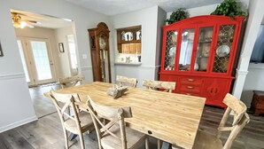 A dining area with a wooden table and chairs, a red china cabinet, and a wall-mounted clock. - Granny's at the Beach…Heated Pool (Panama City Beach)