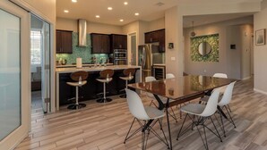 A modern kitchen with dark wooden cabinets, stainless steel appliances, and a central island with bar stools. - Two Resort Style Homes Steps from Each Other, 7 Bedrooms, Pool, Hot Tub, Misters (Cathedral city)