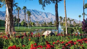 A landscaped area with a lake, palm trees, and a mountain backdrop. - Two Resort Style Homes Steps from Each Other, 7 Bedrooms, Pool, Hot Tub, Misters (Cathedral city)