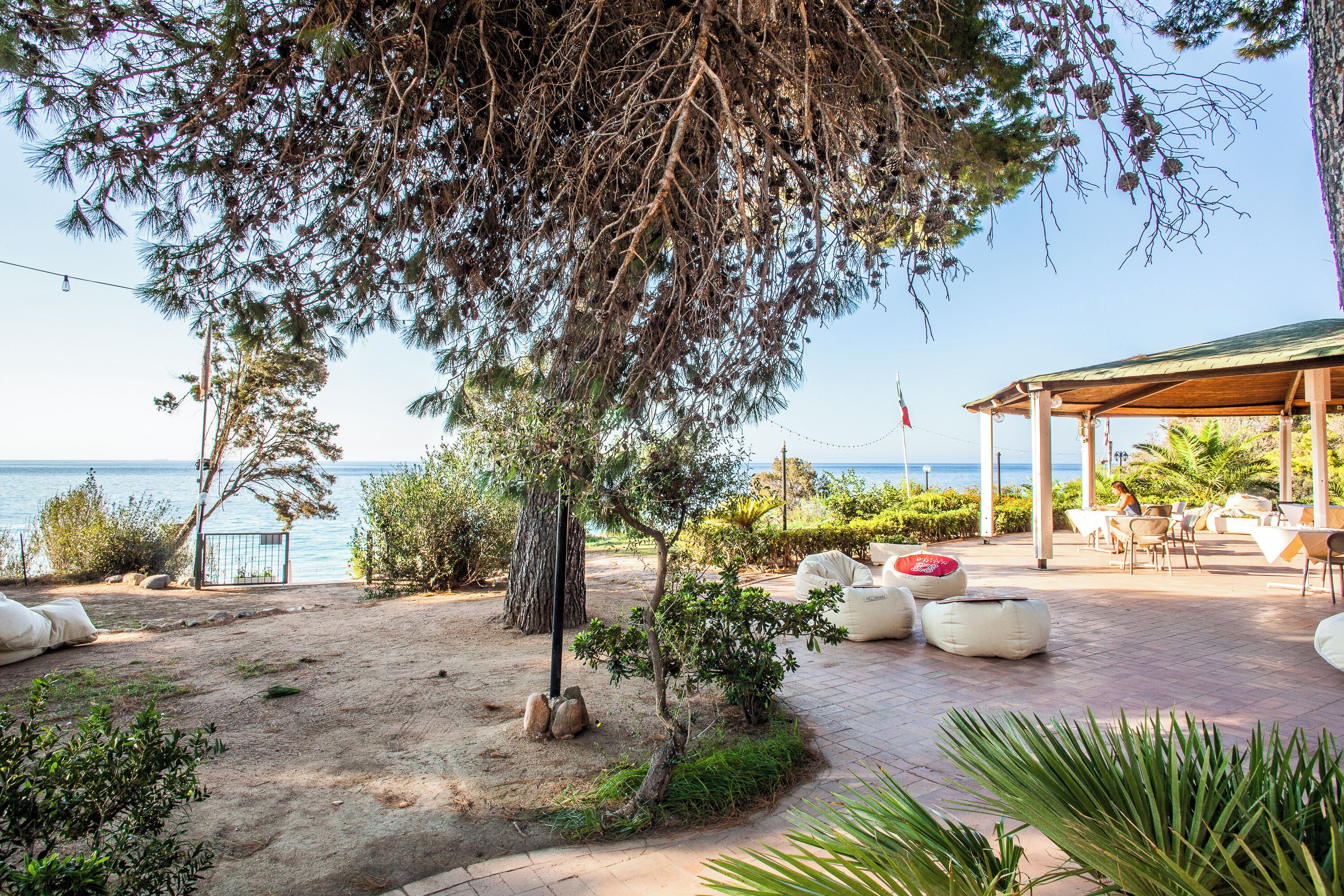 A patio area with outdoor seating, a pergola, and a view of the sea.