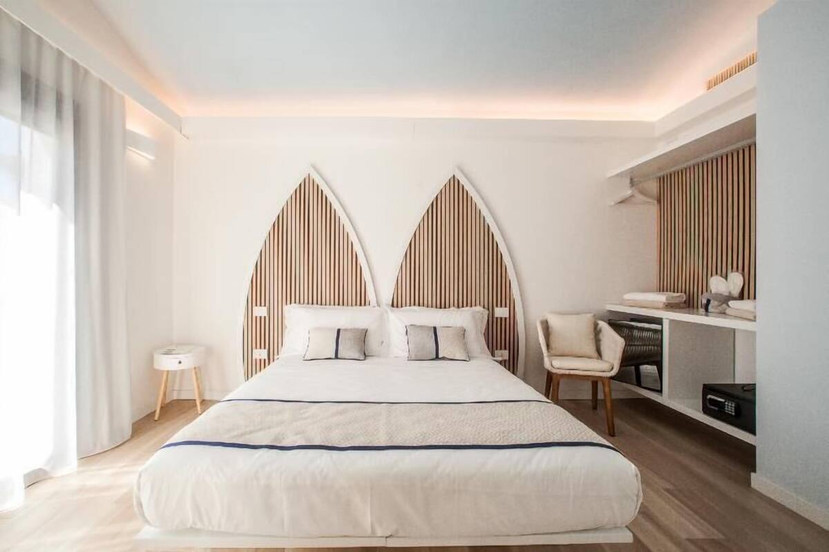A modern hotel room with a large bed, a desk with a chair, and a view of the city.
