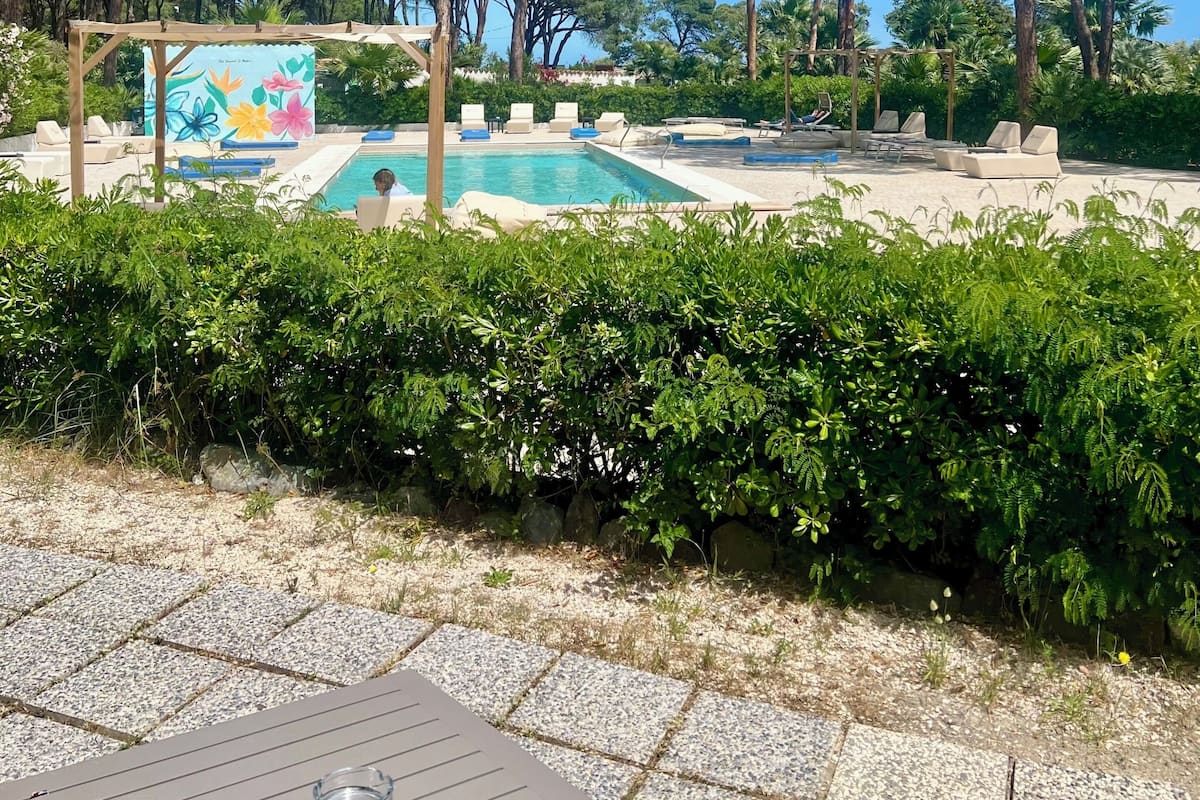 A pool area with lounge chairs, a pergola, and a mural.