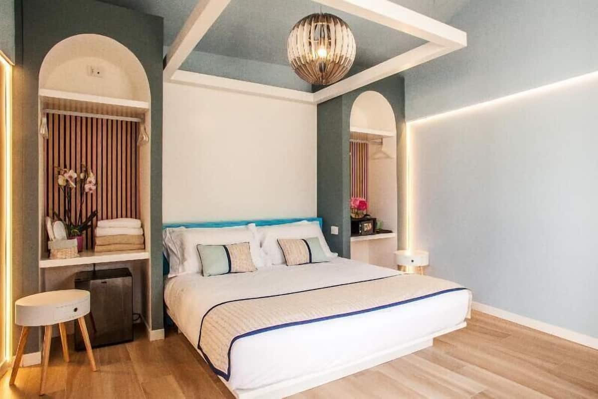 A modern bedroom with a large bed, a vanity with a mirror, and a hanging light fixture.
