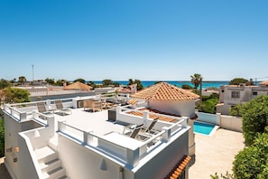 A rooftop terrace with outdoor seating, a swimming pool, and a view of the sea.