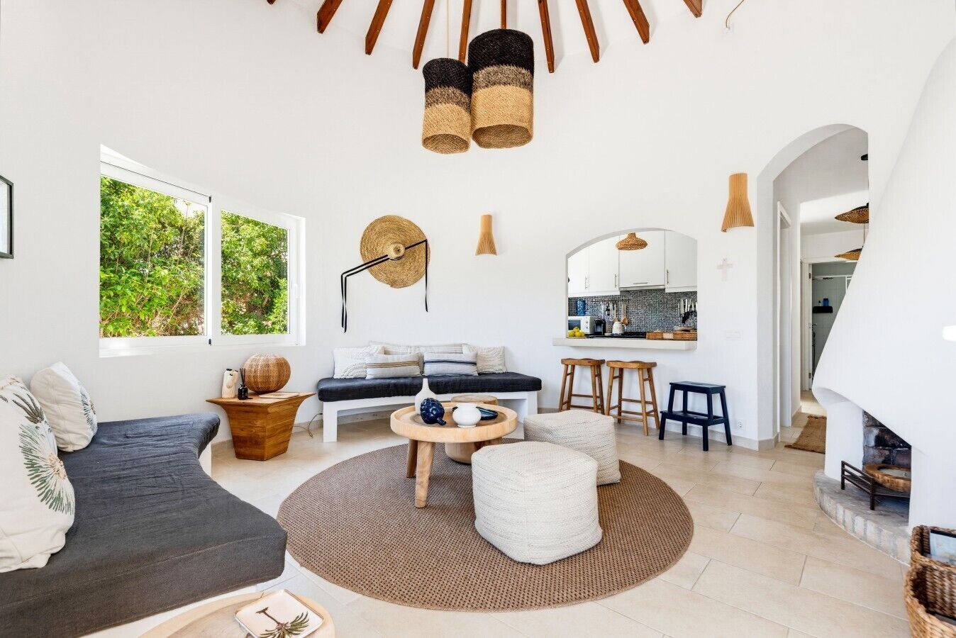 Ein modernes Wohnzimmer mit einer Couch, einem Couchtisch und einem Hocker, einem Küchenbereich mit Barhocker und einem Kamin.