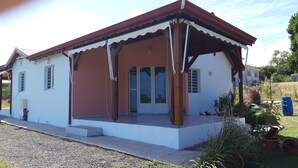 A single-story house with a red roof, white walls, and a covered porch.