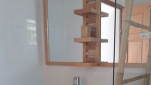 A bathroom with a wooden vanity, a green sink, and a mirror above it.