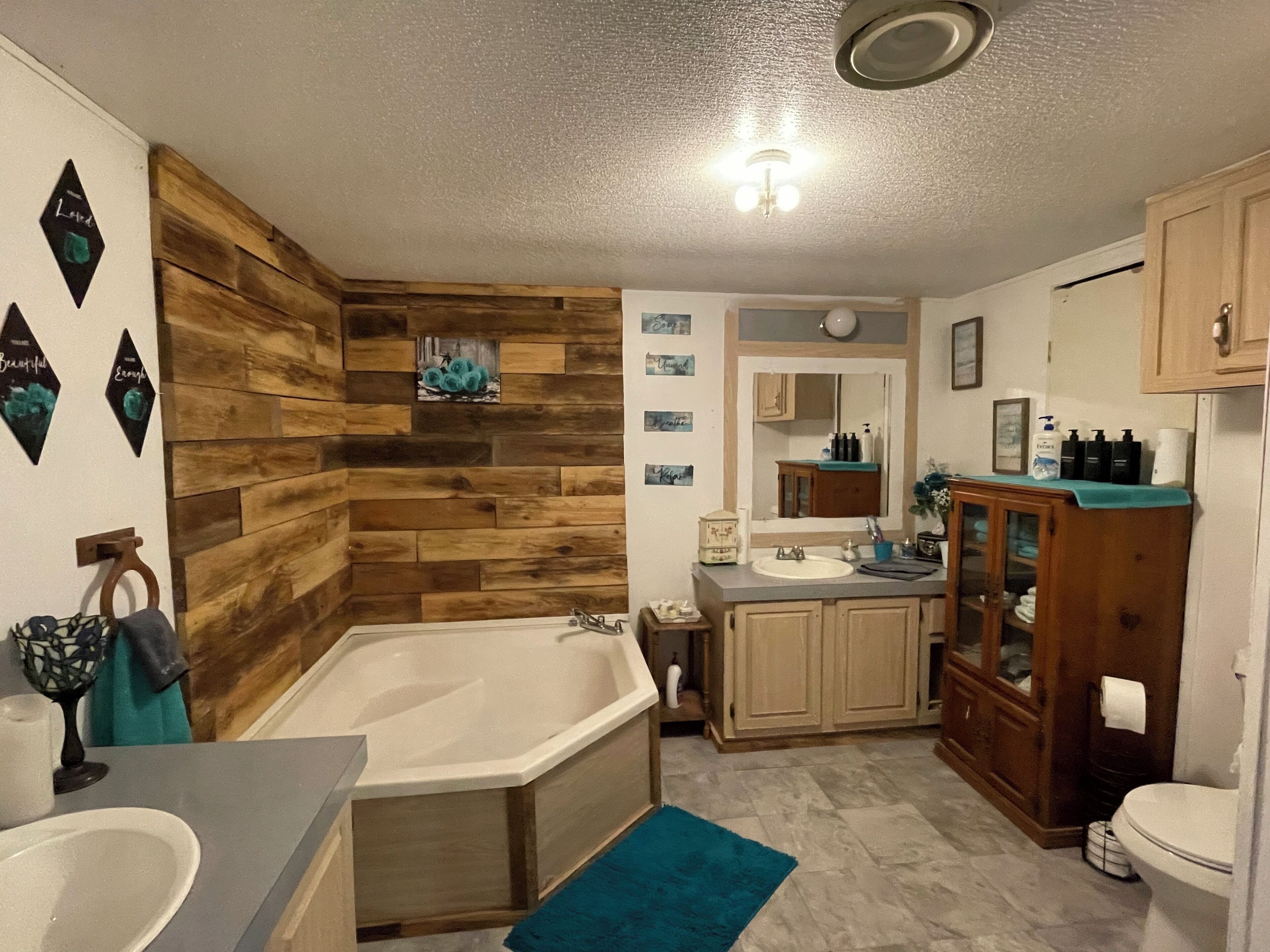 A bathroom with a wooden wall, a bathtub, a sink, and a cabinet.
