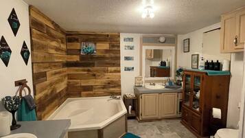A bathroom with a wooden wall, a bathtub, a sink, and a cabinet.