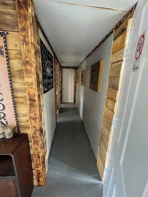 Een smalle gang met houten lambrisering, een rookverbodsgevaarte en een deur aan het einde.