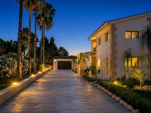 A modern house with a driveway leading to a garage, surrounded by palm trees and well-lit outdoor areas. - Vacation villa Casa Mia Luxuriously furnished vacation villa with pool. (Marratxi)