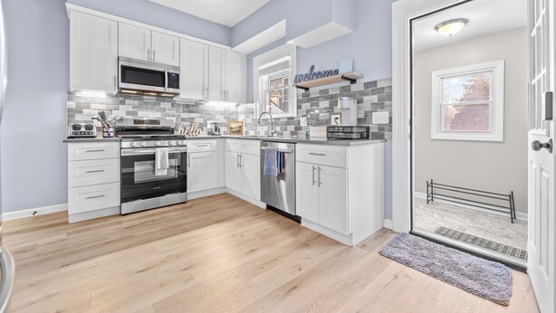 A modern kitchen with white cabinets, a stainless steel oven, a microwave, and a dishwasher. - Luxe Ohio City Townhome only minutes to stadium! (Cleveland)