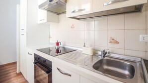 Una cocina moderna con armarios blancos, un fregadero de acero inoxidable y una hornilla negra.