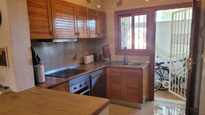 A kitchen with wooden cabinets, a stainless steel sink, and a tiled backsplash. - Anacasa Duplex Marineta Bot DUP2136 (Denia)
