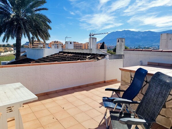 A rooftop terrace with a table, chairs, and a palm tree. - Anacasa Duplex Marineta Bot DUP2136 (Denia)