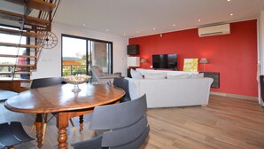 Un salon moderne avec un coin repas, un mur d’accent rouge et une grande fenêtre.