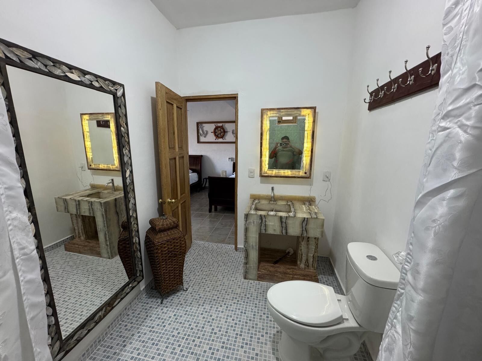 A bathroom with two sinks, a toilet, and a large mirror.
