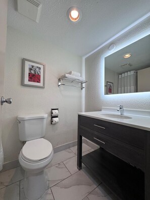 A bathroom with a toilet, a sink with a mirror, and a towel rack.