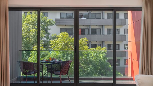 Ein Balkon mit Tisch und Stühlen, Blick auf ein Gebäude und eine Couch im Vordergrund.