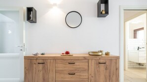 A modern kitchen with a wooden cabinet, a round mirror, and decorative items on the countertop.