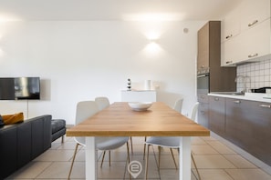Uma cozinha moderna com armários brancos, uma mesa de jantar de madeira e um sofá de couro preto.