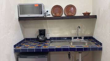 A compact kitchen with a microwave, coffee maker, sink, and a small refrigerator.