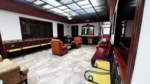 A spacious room with a high ceiling, a long bench along the wall, and several armchairs. - Lodging in the center with gym and parking included. (Loja)