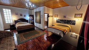 A hotel room with two beds, a wooden ceiling, a chandelier, a large window, and a marble accent wall. - Lodging in the center with gym and parking included. (Loja)